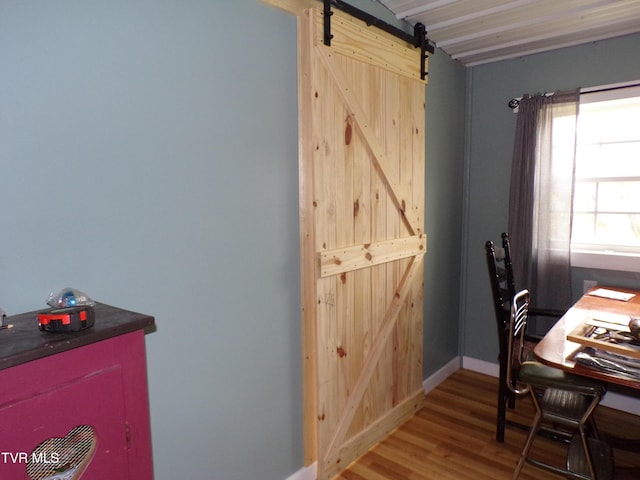 office space featuring a barn door, wood finished floors, and baseboards