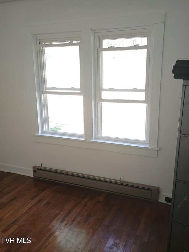 empty room with a baseboard radiator and dark wood-type flooring