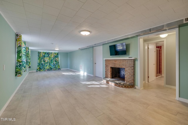 unfurnished living room featuring a brick fireplace and light hardwood / wood-style flooring