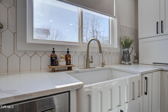 kitchen with white cabinets, light stone counters, plenty of natural light, and sink