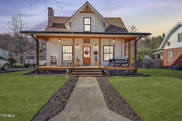 modern inspired farmhouse with a lawn, covered porch, and central air condition unit