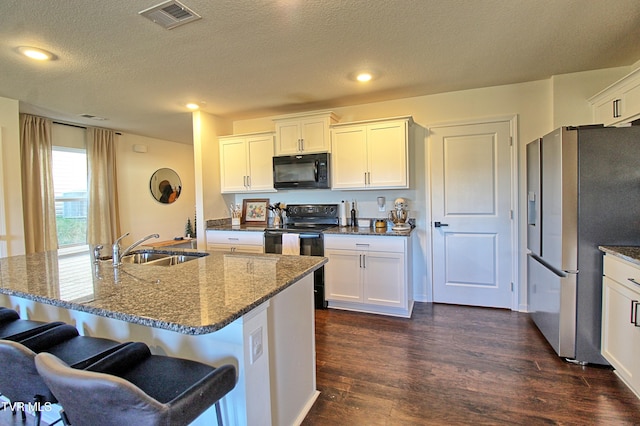 kitchen with dark hardwood / wood-style flooring, sink, a center island with sink, and black appliances