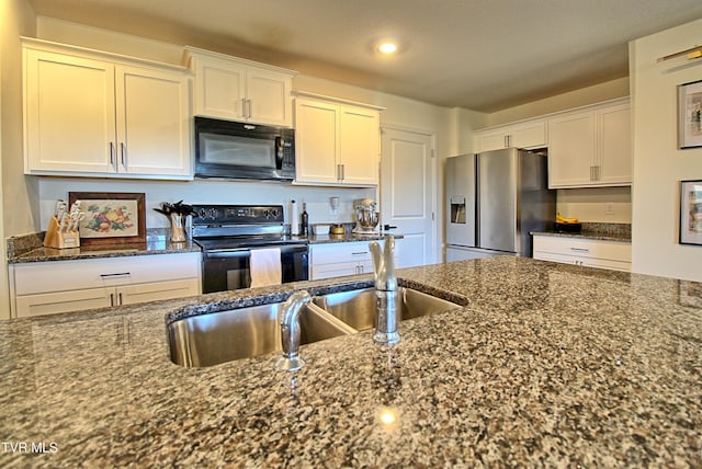 kitchen featuring white cabinetry, dark stone countertops, and black appliances