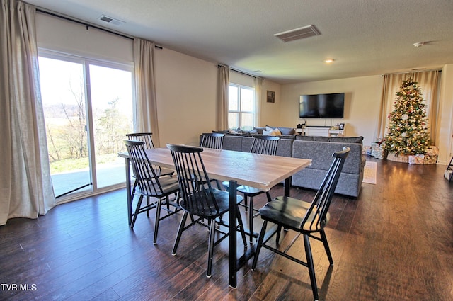 dining area with a textured ceiling and dark wood-type flooring