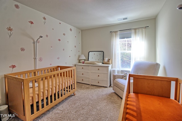 carpeted bedroom with a textured ceiling and a crib