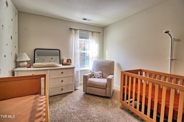 carpeted bedroom featuring a crib and a textured ceiling