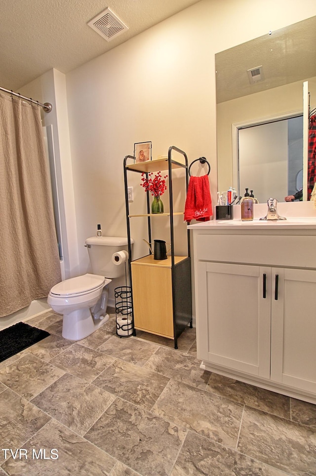 bathroom with vanity, toilet, and a textured ceiling