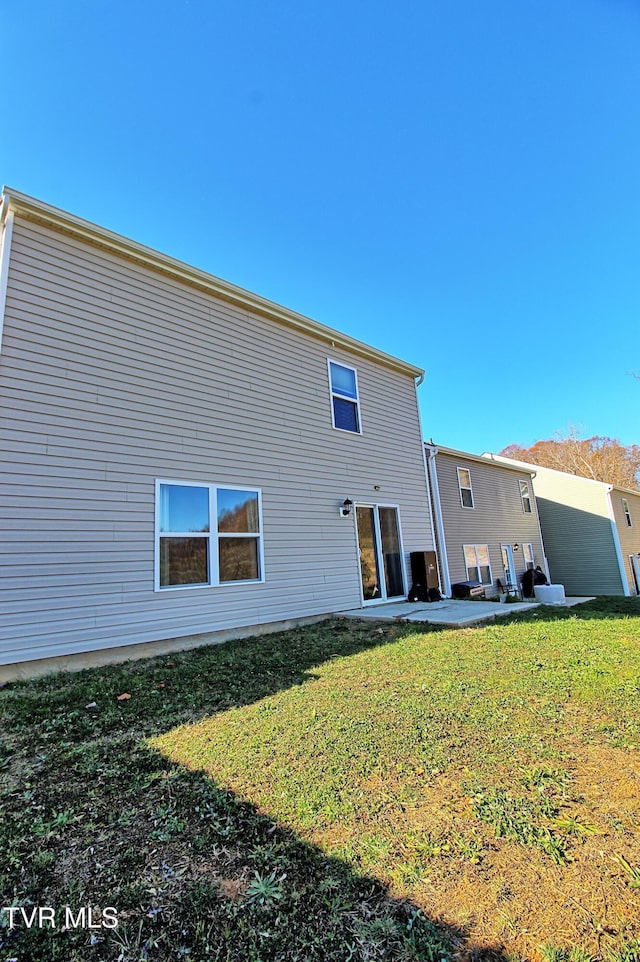 rear view of house featuring a lawn and a patio