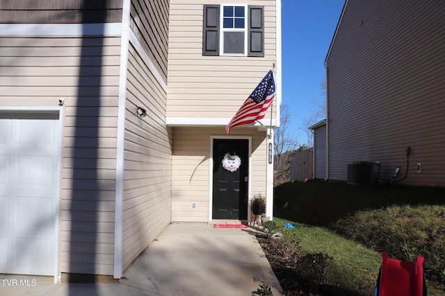 doorway to property with a garage and central AC unit