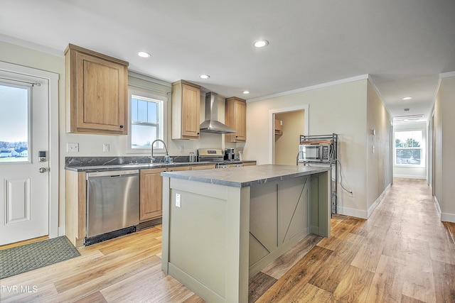 kitchen featuring appliances with stainless steel finishes, light wood-type flooring, ornamental molding, wall chimney exhaust hood, and a center island