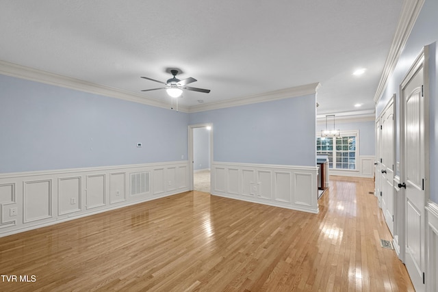 unfurnished room with ceiling fan with notable chandelier, light hardwood / wood-style flooring, and crown molding