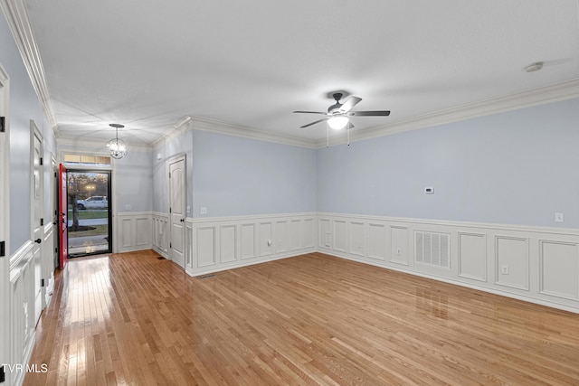 spare room featuring ceiling fan with notable chandelier, light hardwood / wood-style floors, and ornamental molding