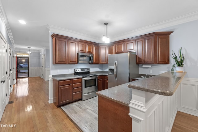 kitchen featuring kitchen peninsula, appliances with stainless steel finishes, ornamental molding, pendant lighting, and light hardwood / wood-style floors