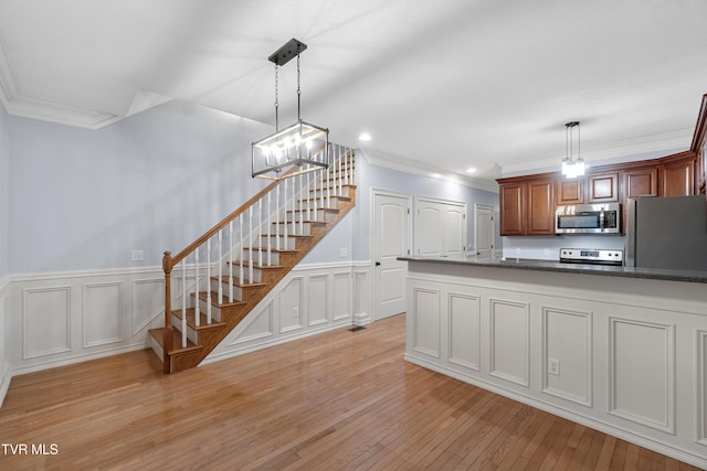 kitchen featuring ornamental molding, decorative light fixtures, light hardwood / wood-style floors, stainless steel appliances, and a chandelier