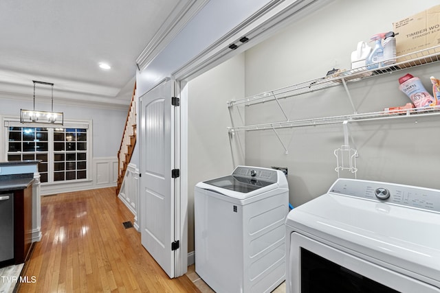 laundry area with wood-type flooring, ornamental molding, and independent washer and dryer