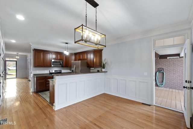 kitchen with kitchen peninsula, crown molding, pendant lighting, light hardwood / wood-style floors, and appliances with stainless steel finishes