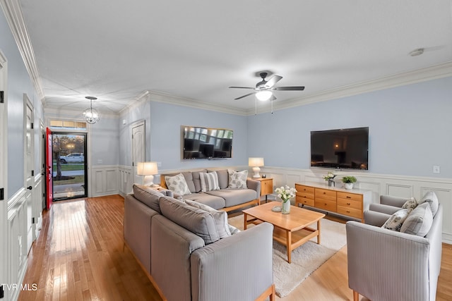 living room featuring crown molding, ceiling fan with notable chandelier, and light wood-type flooring