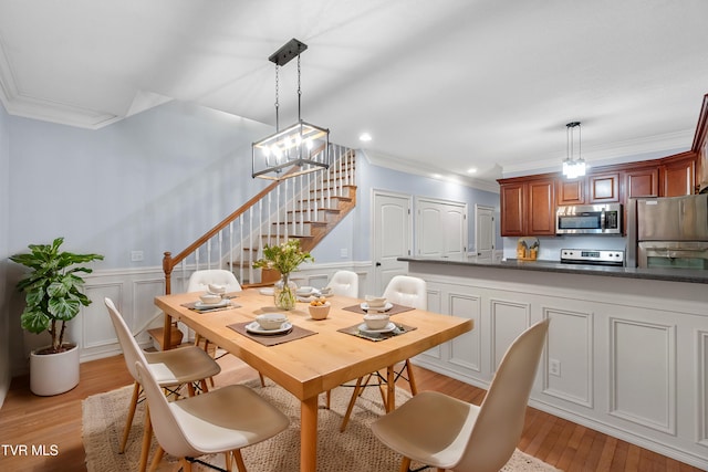 dining area featuring light hardwood / wood-style flooring, a notable chandelier, and ornamental molding