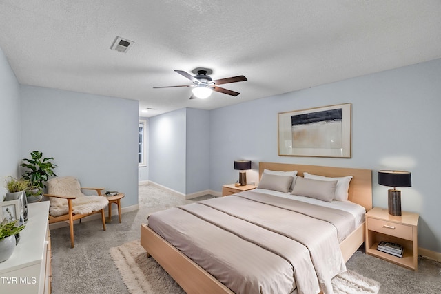bedroom featuring ceiling fan, light colored carpet, and a textured ceiling