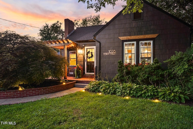 view of front of house with a pergola and a lawn