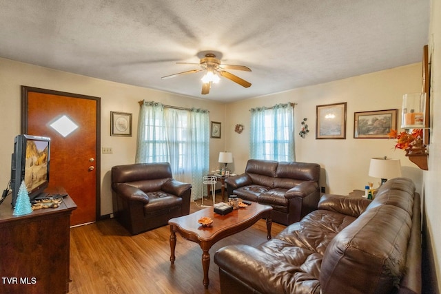 living room with ceiling fan, a textured ceiling, and light hardwood / wood-style flooring