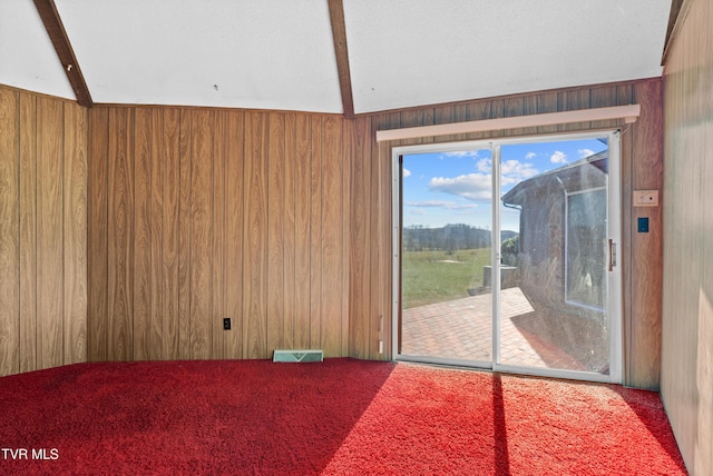 empty room featuring carpet flooring, vaulted ceiling with beams, and wooden walls