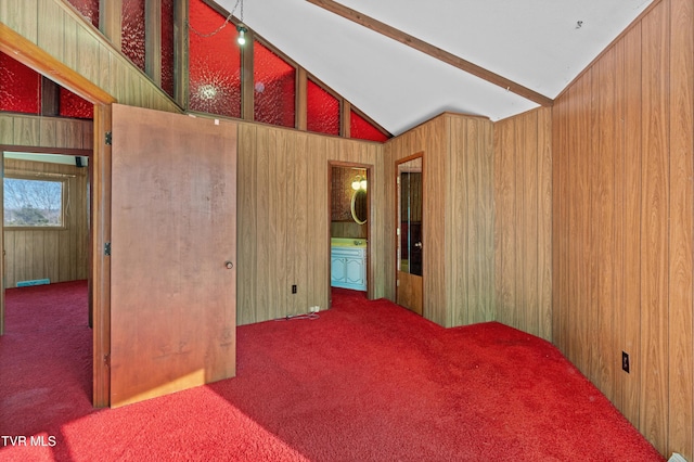 carpeted empty room featuring lofted ceiling with beams and wood walls