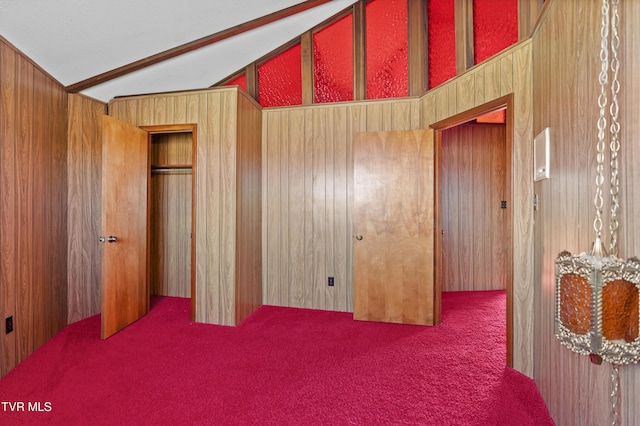 carpeted bedroom with lofted ceiling and wood walls