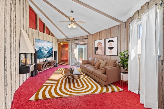 living room featuring wood walls, carpet, lofted ceiling with beams, and ceiling fan