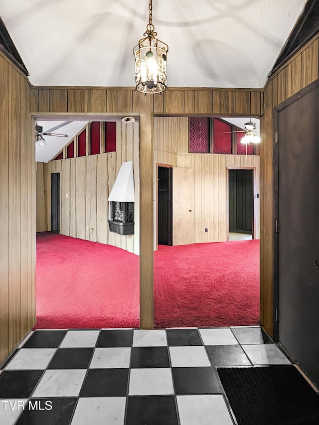 spare room with wooden walls, ceiling fan with notable chandelier, and vaulted ceiling