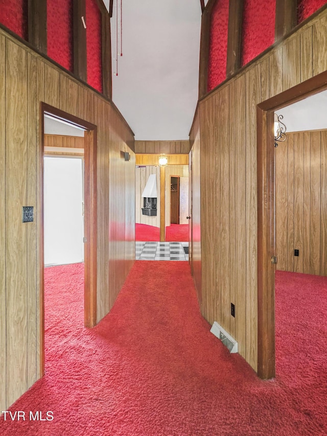 hallway featuring carpet, lofted ceiling, and wooden walls