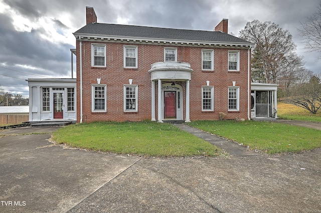 colonial-style house with a front lawn and a sunroom