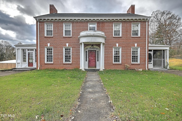 colonial inspired home with a sunroom and a front yard