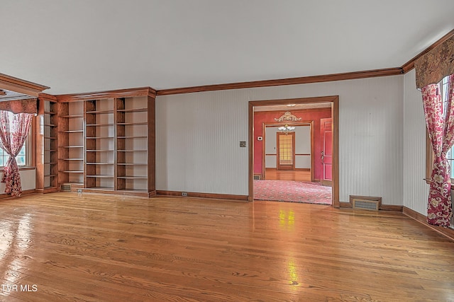 unfurnished living room featuring hardwood / wood-style flooring and crown molding