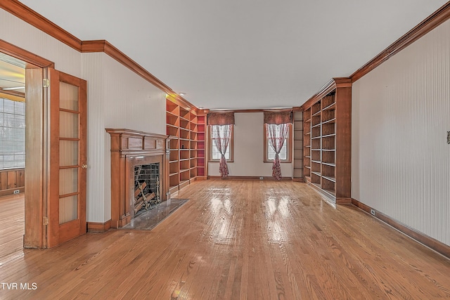 unfurnished living room with built in shelves, a healthy amount of sunlight, and light wood-type flooring