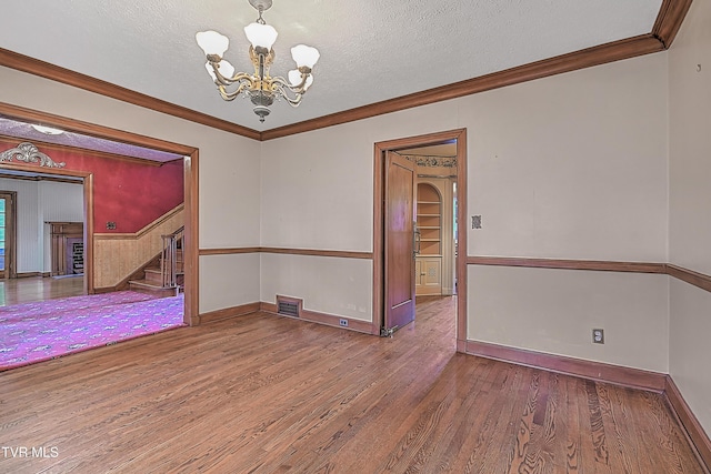 empty room featuring a notable chandelier, crown molding, wood-type flooring, and a textured ceiling