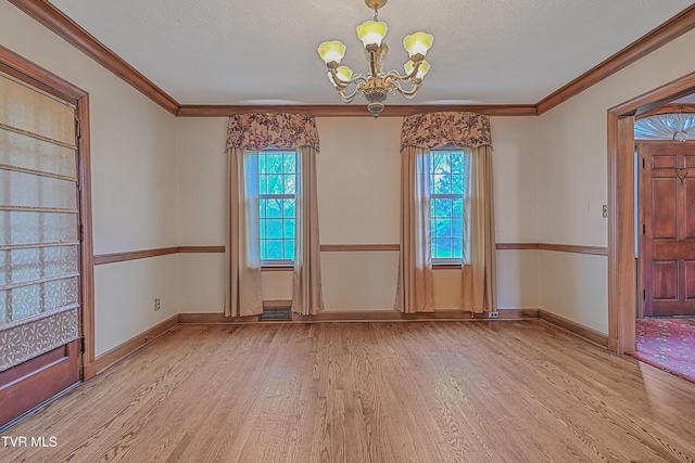 unfurnished dining area with crown molding, a chandelier, a textured ceiling, and light wood-type flooring