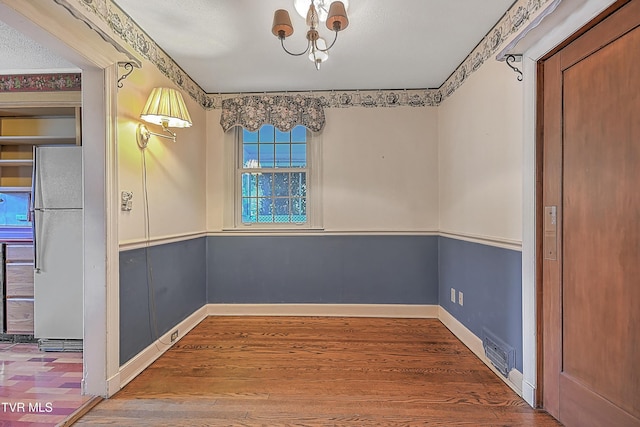 empty room with a textured ceiling, hardwood / wood-style flooring, and ornamental molding