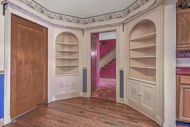 corridor with dark hardwood / wood-style floors and built in shelves