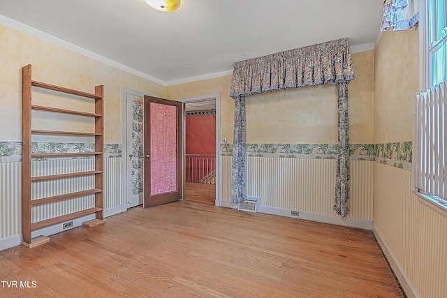 interior space featuring hardwood / wood-style floors, ornamental molding, and french doors