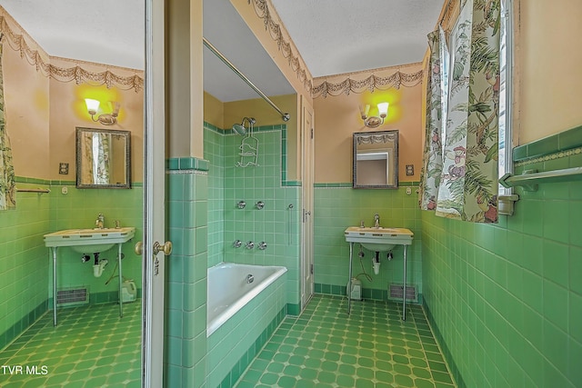 bathroom with a textured ceiling, sink, plus walk in shower, and tile walls