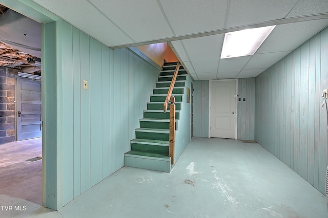 basement with a paneled ceiling and wood walls