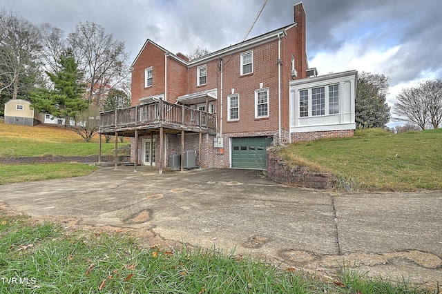 back of property featuring a lawn, central AC, a deck, and a garage