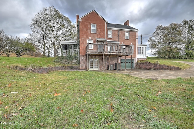 back of house featuring a garage, a yard, a wooden deck, and central AC