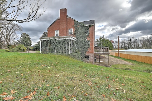 back of property featuring a wooden deck and a lawn