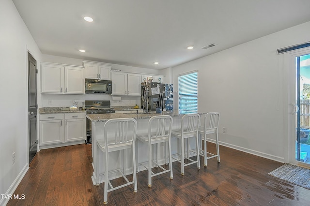 kitchen with dark hardwood / wood-style flooring, a center island with sink, white cabinetry, and black appliances