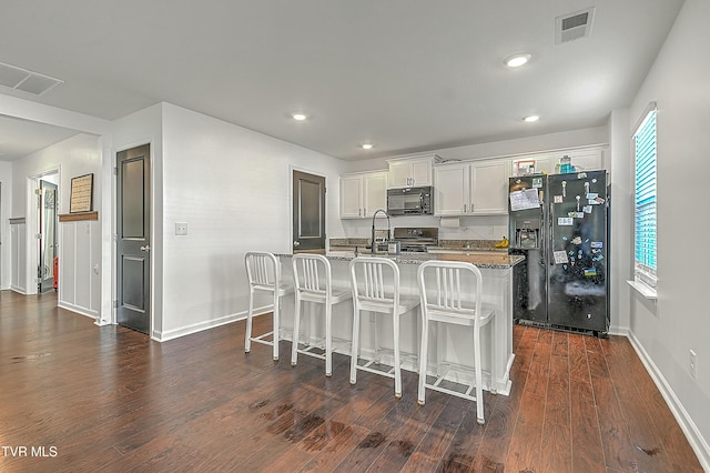 kitchen featuring black appliances, white cabinets, a center island with sink, dark hardwood / wood-style floors, and stone countertops