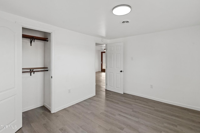 unfurnished bedroom with wood-type flooring and a closet