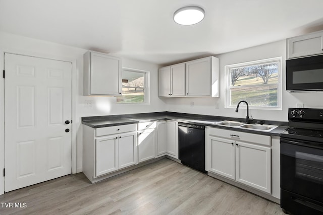 kitchen featuring sink, a wealth of natural light, black appliances, white cabinets, and light wood-type flooring