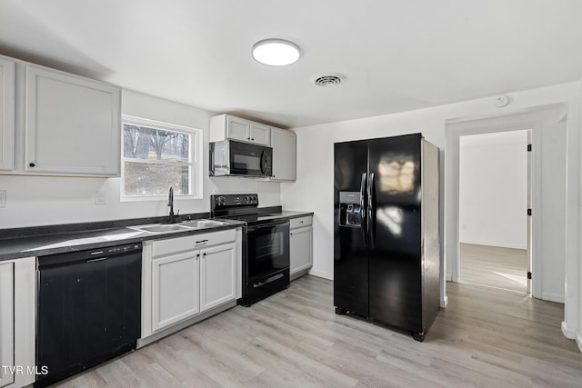 kitchen with light wood-type flooring, white cabinets, sink, and black appliances